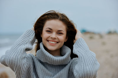 Portrait of smiling young woman standing at beach