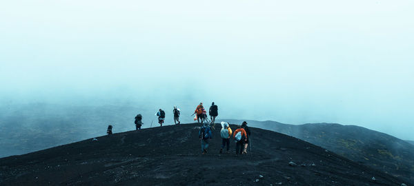 People walking on mountain during foggy weather