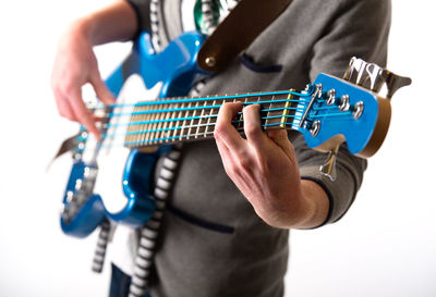 Close-up midsection of man playing guitar against white background