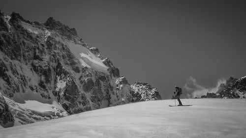 Person walking on snowcapped mountain against sky