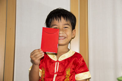 Portrait of smiling boy holding red door