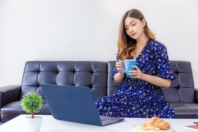 Young woman using phone while sitting on table