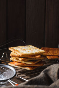 Square dry crackers biscuit on a wooden table. wooden texture dark background. snack dry biscuits 