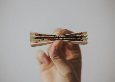 Close-up of hand holding paper against white background