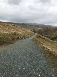 Road amidst land against sky