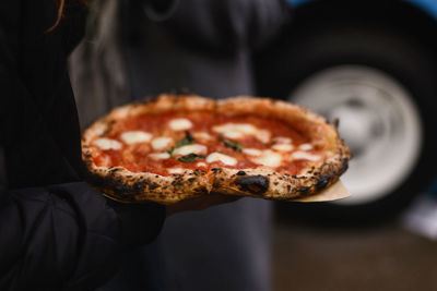 Close-up of hand holding pizza