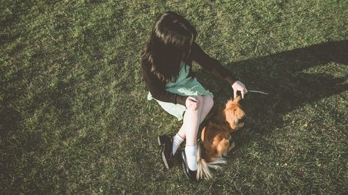 Rear view of woman with dog on grassy field