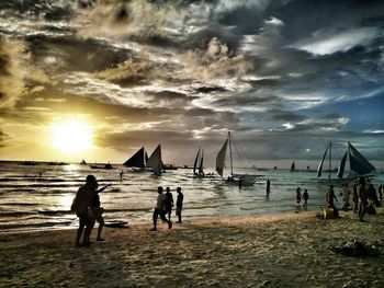 People on beach against sky during sunset