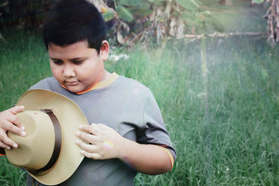 The boy with a hat behind his is a tree with soft sunlight.