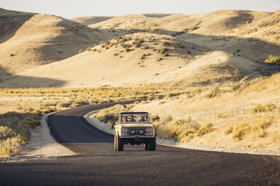 Female friends in off-road vehicle amidst field during road trip