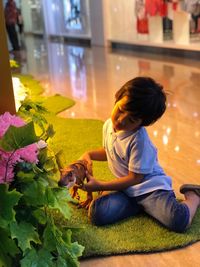 Boy playing with toy while sitting on floor