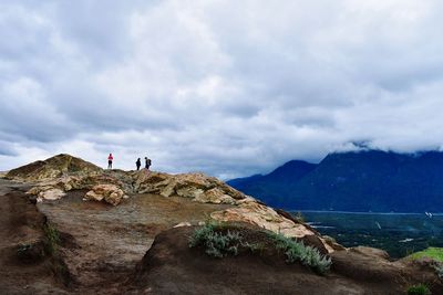 People standing on rock against sky