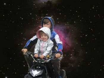 Full length of boy riding siblings at night