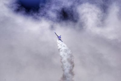 Low angle view of airplane flying in cloudy sky during airshow