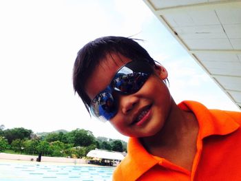 Portrait of smiling boy wearing sunglasses against sky