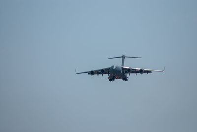 Low angle view of c17 airplane flying against clear sky