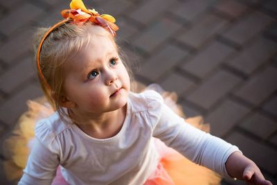 High angle view of cute girl looking up while standing on footpath