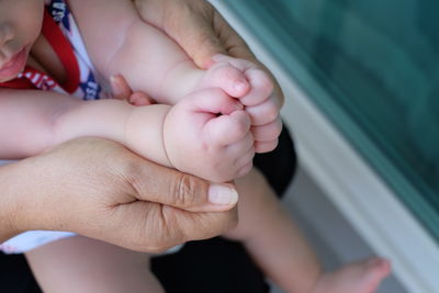 Midsection of woman holding baby hands