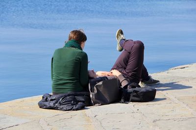 Rear view of people sitting on beach