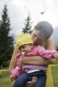 Mother carrying cute daughter while standing outdoors