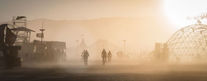 Men in city against sky during sunset