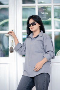 Portrait of young woman wearing sunglasses while standing in bathroom