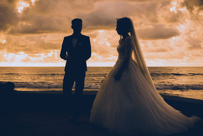 Silhouette couple standing on beach during sunset