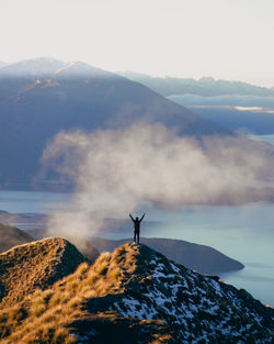 Man standing on rock against sky