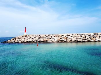 Lighthouse by sea against sky