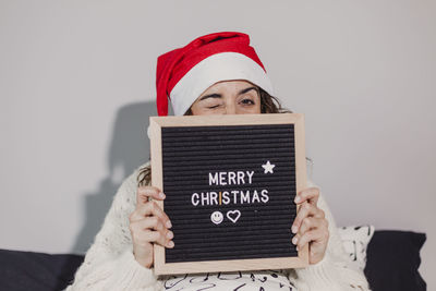 Portrait of woman winking with merry christmas text at home