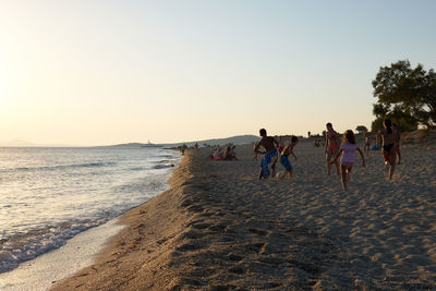 People on beach against clear sky