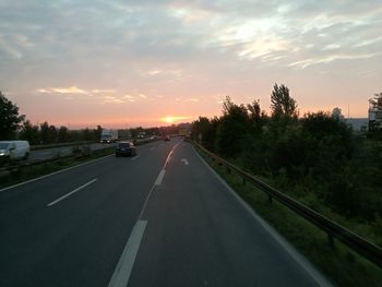 Road in city against sky at sunset