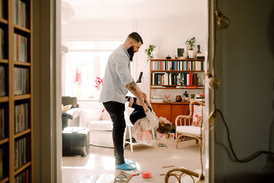 Full length of father swinging daughter in living room at home