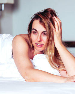 Portrait of young woman lying on bed at home