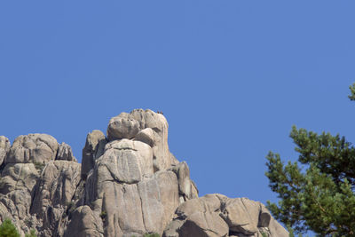 Low angle view of rock formation against clear blue sky