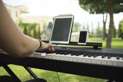 Midsection of woman playing piano in yard
