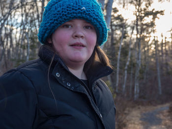 Portrait of girl standing against trees in forest during winter