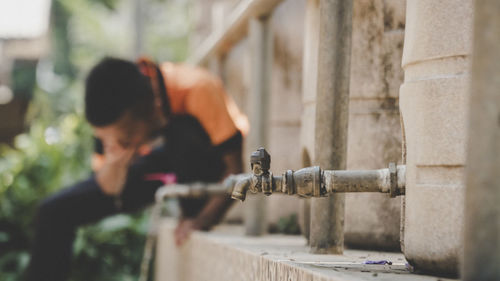 Close-up of faucet with man in background