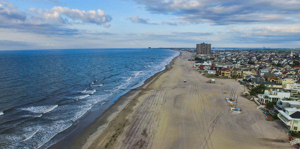 Aerial view of seascape by residential district against cloudy sky