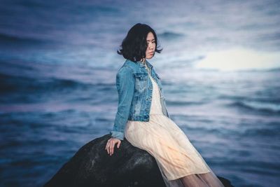 Young woman standing on beach against sky