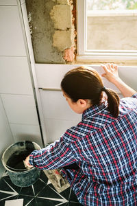 Mason taking cement from bucket to lay bathroom tiles