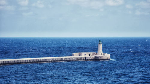 Lighthouse by sea against sky