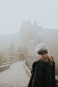 Rear view of woman standing against historic building during winter