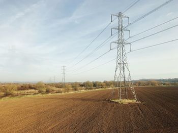 Electricity pylon on field against sky