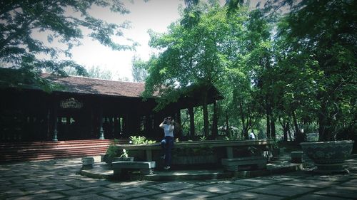 Woman in front of building against trees