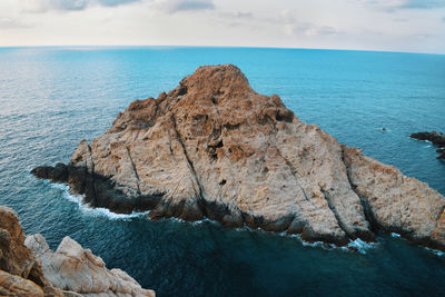 Rock formation on sea shore against sky