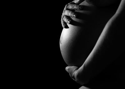 Midsection of pregnant woman in darkroom