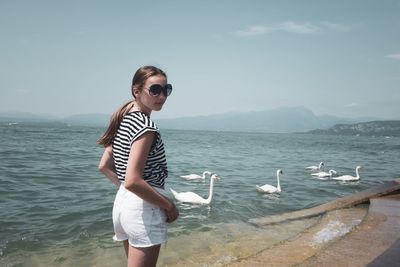 Full length of teenager girl standing in sea against sky