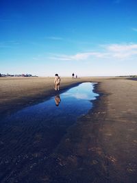 Boy reflecting in water at beach