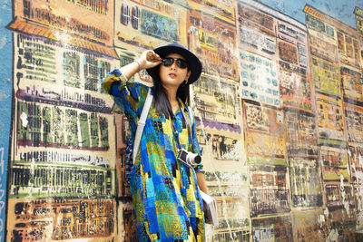 Portrait of young woman standing against graffiti wall